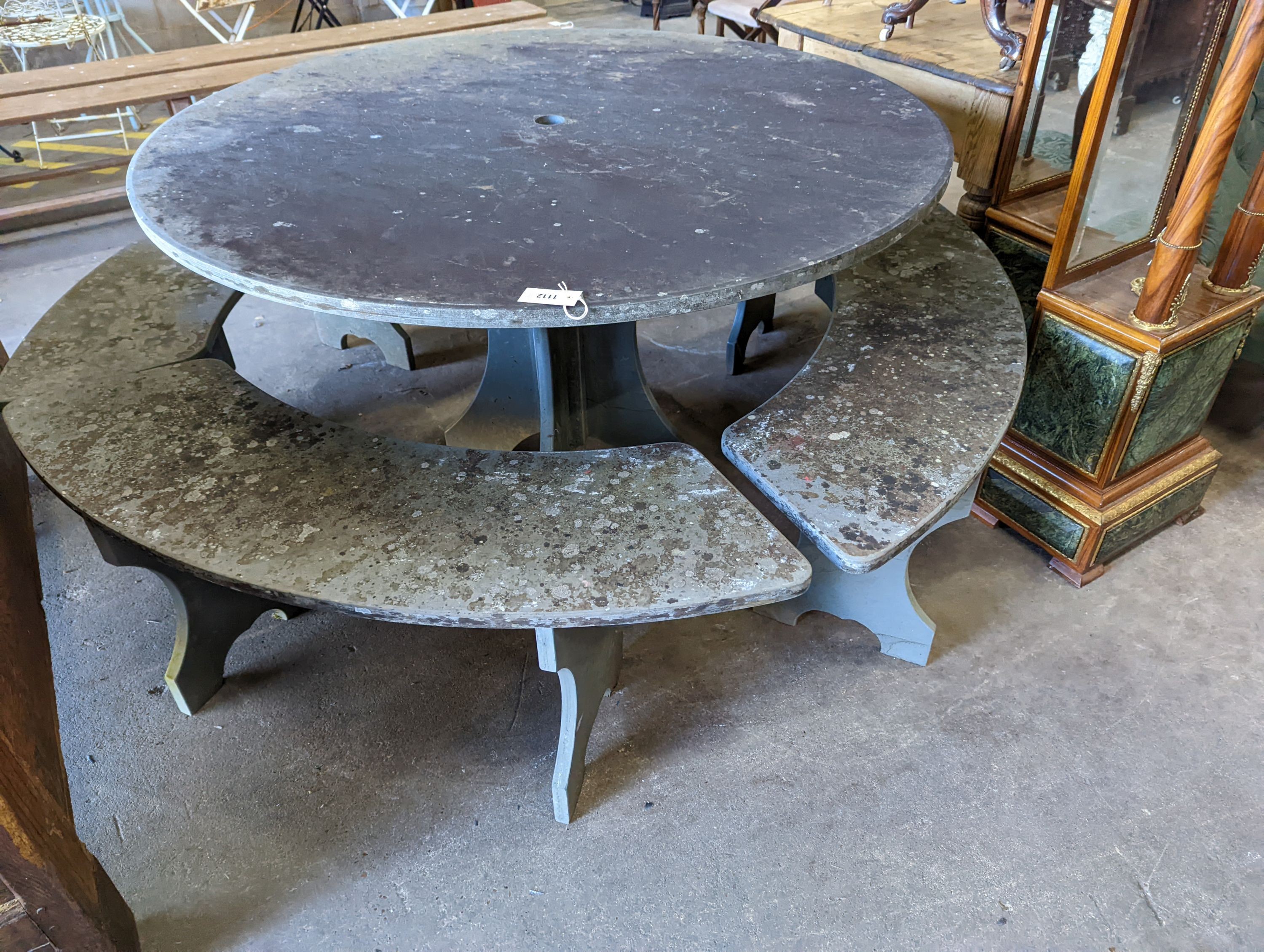 A heavy slate circular topped garden table, diameter 125cm, height 79cm together with four crescent shaped slate garden benches